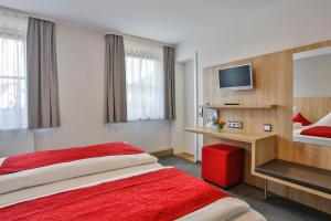 バート・ディッツェンバッハにあるGasthof Restaurant Hirschの赤いベッドとテレビが備わるホテルルームです。