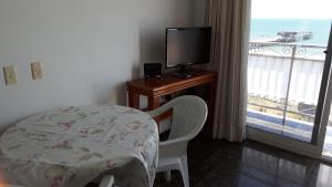 a bedroom with a table and a television and a balcony at Apartamento Beira mar in Fortaleza