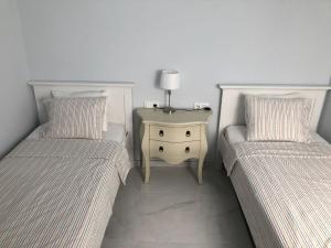 two beds in a room with a night stand and a table at 2 bedroom apartment in the old town, close to the beach in L'Escala