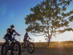 two people riding bikes down a road next to a tree at Pousada Trijunção in Rodeador