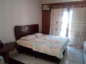 a bedroom with a bed and a window with curtains at Pousada Kantuta in Mucuri +20 photos