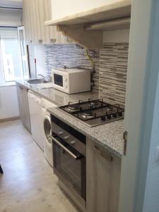 a kitchen with a stove and a microwave at Chainha's Dream Apartment in Sesimbra
