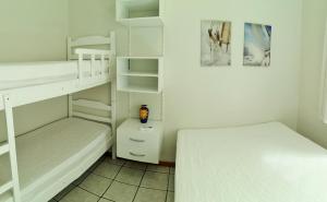 a white bedroom with two bunk beds at Apto na quadra do mar em Meia Praia Itapema, 2 dorm, 6 pessoas in Itapema