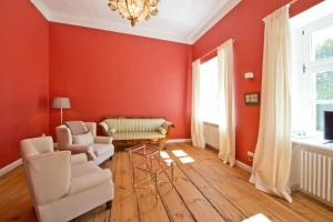 a living room with red walls and chairs and a chandelier at Schloss Retzow Apartments in Retzow