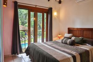 a bedroom with a bed and a large window at Villas Macondo in Tamarindo