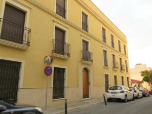 un edificio amarillo con coches estacionados frente a él en Apartamento barrio San Miguel, en Jerez de la Frontera