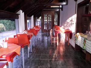 een leeg restaurant met rode tafels en stoelen bij Petit Hotel Caraguata in Puerto Iguazú