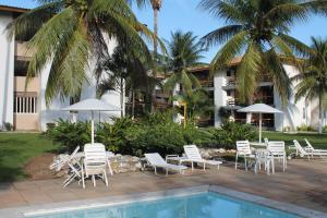 a group of chairs and umbrellas next to a pool at Flat Ilhéus - Jubiabá Olivença in Ilhéus