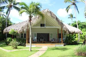 Willa z krytym strzechą dachem i palmami w obiekcie Caribbean Beach Villa Playa Bonita Las Terrenas w mieście Las Terrenas