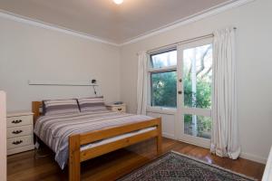 a bedroom with a bed and a large window at Point Lonsdale Beach House in Point Lonsdale