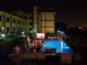 un grupo de personas de pie alrededor de una piscina por la noche en PrimeBiz Hotel Karawang, en Cikampek
