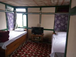 Habitación pequeña con 2 camas y TV. en Vamoose Nehabo en Hāpoli
