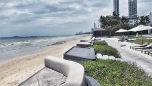 a row of white lounge chairs on the beach at Veranda Pattaya by Lux in Jomtien Beach