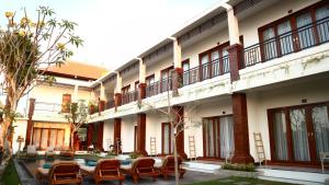 Un patio de un edificio con sillas y mesas. en Seno Guesthouse & Cafe, en Uluwatu