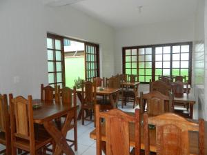 a dining room with tables and chairs and windows at Pousada Flor de Paraty in Paraty