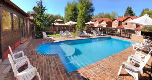 une piscine avec des chaises blanches et une maison dans l'établissement Posada Pfullendorf - Adults Only, à Villa General Belgrano