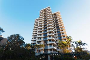 a tall building with palm trees in front of it at Capricornia Apartments in Gold Coast