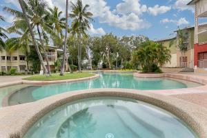 a large swimming pool in a courtyard with palm trees at Amphora Laleuca Apartments Palm Cove in Palm Cove