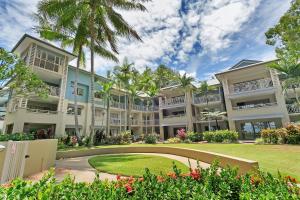 an exterior view of a building with palm trees at Amphora Laleuca Apartments Palm Cove in Palm Cove