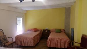 two beds in a room with yellow walls at Hispanoconcucense in Teruel