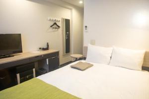 a bedroom with a bed with a desk and a television at Kuretake Inn Nankai Sakai-Ekimae in Sakai