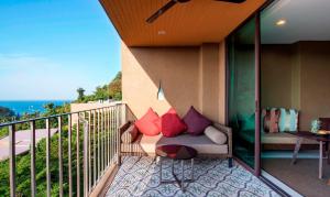 a balcony with a couch with red pillows on it at Sunsuri Phuket - SHA Plus in Nai Harn Beach