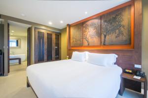 a bedroom with a large white bed and a bathroom at Sunsuri Phuket - SHA Plus in Nai Harn Beach
