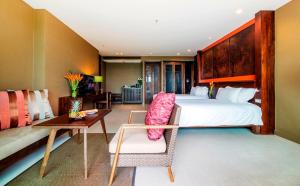 a bedroom with a large bed and a desk and a table at Sunsuri Phuket - SHA Plus in Nai Harn Beach