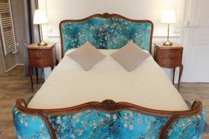 a bed with a blue chair and two night stands at Le Napoléon in Luxeuil-les-Bains