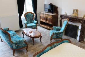 salon z krzesłami, stołem i telewizorem w obiekcie Le Napoléon w mieście Luxeuil-les-Bains