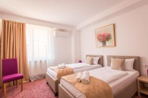 a hotel room with two beds and a purple chair at Pensiunea Simar in Sibiu
