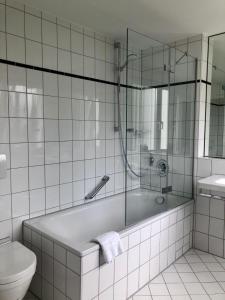 a white bathroom with a tub and a toilet at Hotel Am Park in Leinfelden-Echterdingen