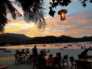 a group of people sitting at tables on the beach at Longtail Beach Resort in Thong Nai Pan Yai