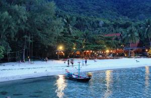 a boat in the water on a beach at night at Longtail Beach Resort in Thong Nai Pan Yai