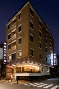 um grande edifício de tijolos numa rua da cidade à noite em Ueno First City Hotel em Tóquio