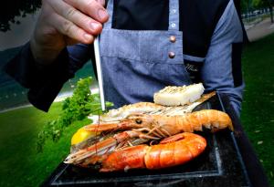 a person holding a tray of seafood on a grill at Parc Hotel Du Lac in Levico Terme
