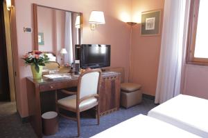 Habitación de hotel con escritorio y TV. en Hotel Bristol, en Milán