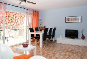 een woonkamer met een tafel en stoelen en een televisie bij Apartment Llavaneres I in Sant Andreu de Llavaneres