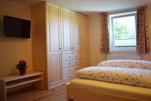 1 dormitorio con 1 cama, TV y ventana en Haus Partale, en Oberstdorf