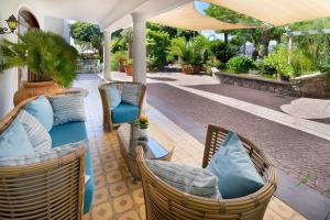 a patio with wicker chairs and blue pillows at Hotel Parco Smeraldo Terme in Ischia