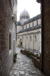 an alley with a building with a dome in the background at Old Town Apartment in Šibenik