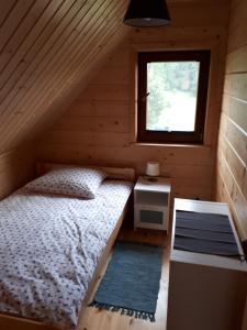 a bedroom with a bed and a window in a log cabin at Domek nad jeziorem Ublik in Miłki