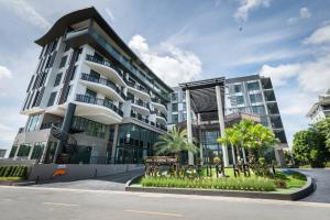 a large white building with palm trees in front of it at The Museum Hotel in Nakhon Pathom