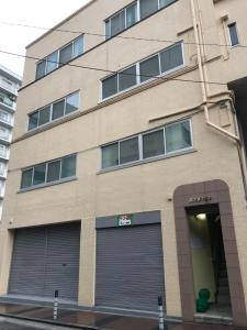 un bâtiment avec deux portes de garage devant lui dans l'établissement GLOCE 横須賀 シェアルーム NAVY BASE l Yokosuka Share room at NAVY BASE, à Yokosuka