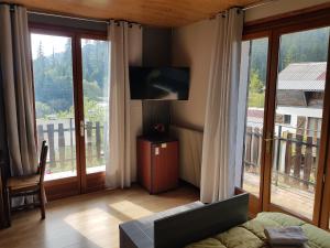 a living room with a television and large windows at Hôtel Les Chamois in La Bollène-Vésubie