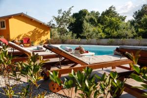 a backyard with a pool with two loungers next to a house at Camp 'Dvor' bell tent accommodation in Manjadvorci