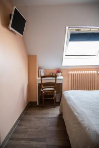 a bedroom with a bed and a desk and a chair at La Longere d'Helene in Lauzach