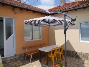 una mesa y sillas bajo una sombrilla en un patio en Guest Rooms Kamberovi, en Shabla