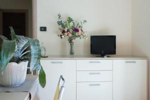 einen weißen Schrank mit einem TV und einer Vase mit Blumen in der Unterkunft CIVICO33 in Rocca Imperiale