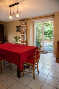 une salle à manger avec une table et des chaises rouges dans l'établissement La Longere d'Helene, à Lauzach